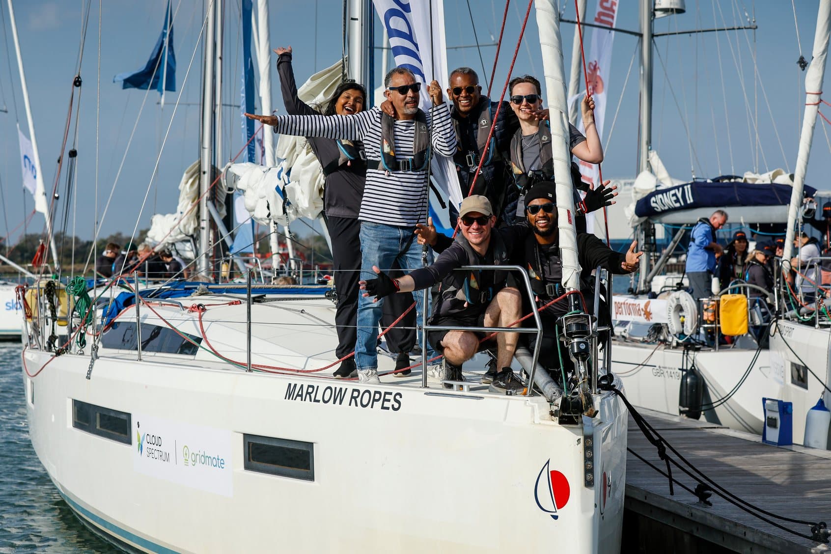 The Cloud Spectrum and Gridmate crew gathered on the deck of the Marlow Ropes yacht at the dock, arms raised.